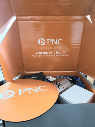 Heather's welcome box which includes various PNC-branded items such as a mousepad, a steel water bottle, etc.